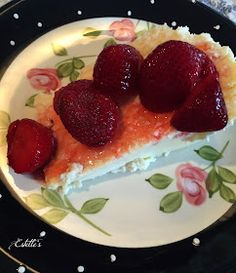 a piece of cheesecake with strawberries on top sits on a flowered plate