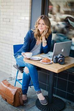 a woman sitting at a table in front of a laptop