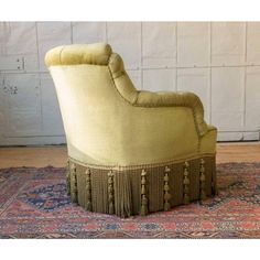 an upholstered chair with tassels on the back