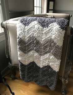 a crocheted blanket sitting on top of a white chair next to a window