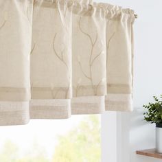 the curtains are hanging on the window sill in front of an open window with a potted plant next to it