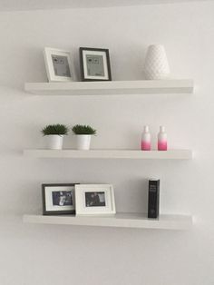 three white shelves with pictures, frames and plants