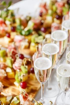 many glasses of champagne are lined up on a table with other food and drink items