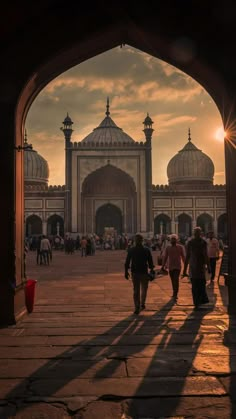 people walking in front of an ornate building at sunset