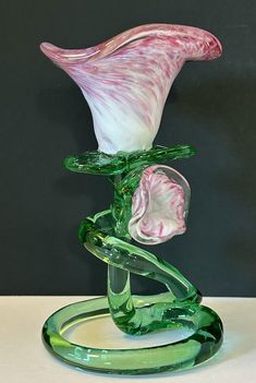 a glass vase sitting on top of a table next to a green object with a flower in it