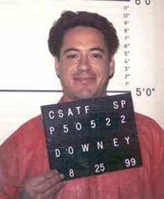 a mug shot of a man holding up a sign that says csaff sp p500522 downey