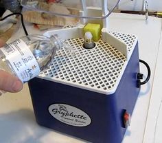 a person is pouring water into an ice chest with fruit and vegetables in it on a table