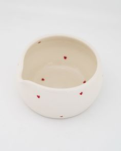 a small white bowl with red hearts on the rim and bottom, sitting on a white surface