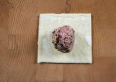 a piece of wax paper on top of a wooden table next to a doughnut