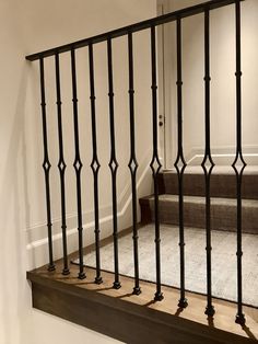 a stair case with black iron railing and wood handrails