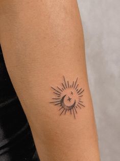 a woman's arm with a small sun and moon tattoo on it