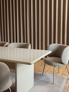 two chairs and a table in front of a wall with vertical striped blinds on it