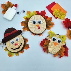 three wooden slices with faces made to look like fall leaves