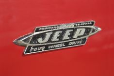 the jeep emblem is on the side of an old red truck