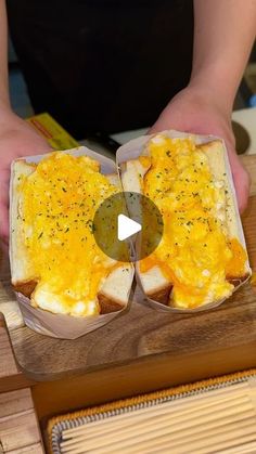 a person holding two halves of bread with eggs in it