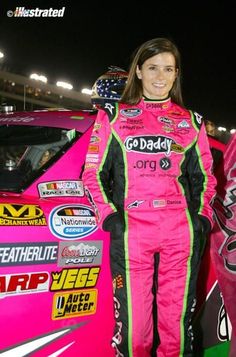 a woman standing next to a pink race car