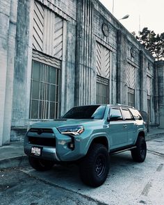 a light blue toyota truck parked in front of an old building with windows and doors