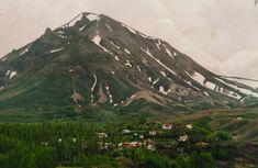 there is a mountain that has snow on it and houses in the valley near by