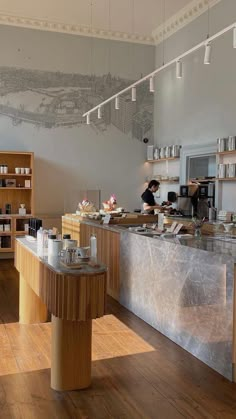 an open kitchen with wooden floors and counter tops, along with two people working behind the counter