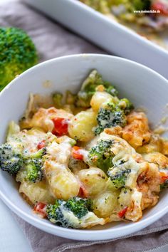 a white bowl filled with broccoli and other food on top of a table