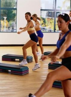 there are many women that are in the gym doing some exercises on treadmills