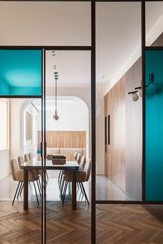 a dining room with glass walls and wooden flooring is seen through the sliding doors