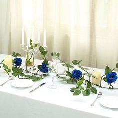 the table is set with blue roses and candles