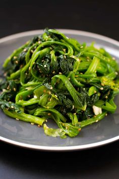 a white plate topped with green vegetables on top of a table