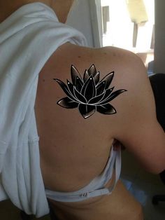 a woman with a tattoo on her back has a lotus flower tattooed on her shoulder