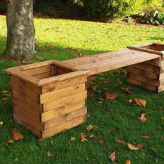 a wooden bench sitting on top of a lush green field next to a large tree