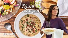 a woman holding a plate of food next to a bowl of soup