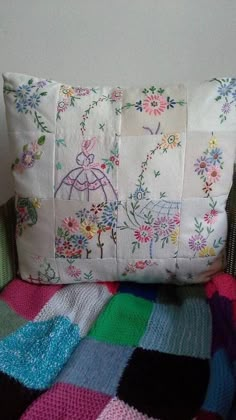 a pillow that is sitting on top of a chair next to a blanket with flowers