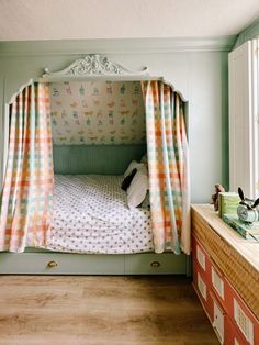 a bedroom with a bed, dresser and curtained canopy over it's headboard