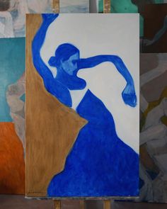 an abstract painting of a woman in blue is shown on easel with other paintings behind it