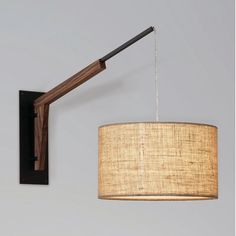 a lamp that is on the wall next to a light fixture with a fabric shade