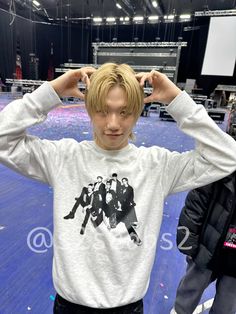 a young man standing in front of a stage with his hands on his head and looking at the camera