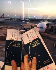 two people holding up their passport in front of an airplane