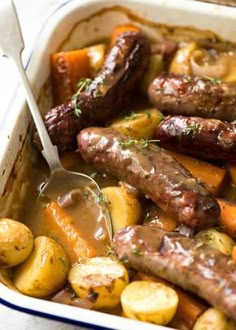 sausages, potatoes and carrots in a dish with a spoon