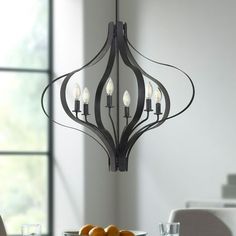 a chandelier hanging over a dining room table with fruit on the plate in front of it