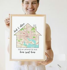 a woman holding up a framed map with the words, home sweet home on it