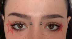 a close up of a person's face with piercings on her nose and eyebrows