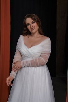 a woman in a white dress is posing for a photo with her hands on her hips