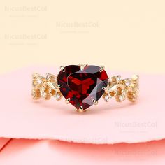 a red heart shaped ring sitting on top of a pink surface