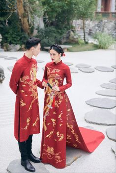 a man and woman dressed in traditional chinese clothing standing next to each other on the ground