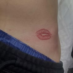 a woman's stomach with a red lip tattoo on her lower body and side