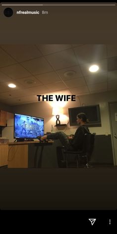 a man sitting at a desk in front of a tv