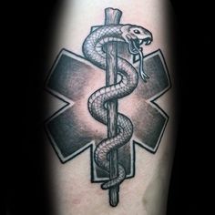 a snake wrapped around a medical symbol tattoo on the arm, with a cross in the background