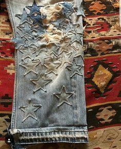 an old pair of jeans with holes and stars on them sitting on top of a rug