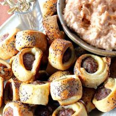 hot dogs wrapped in bread and topped with poppy seed sprinkles next to a bowl of mashed potatoes