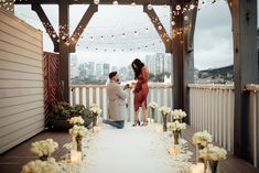 two people standing on a deck with candles and flowers